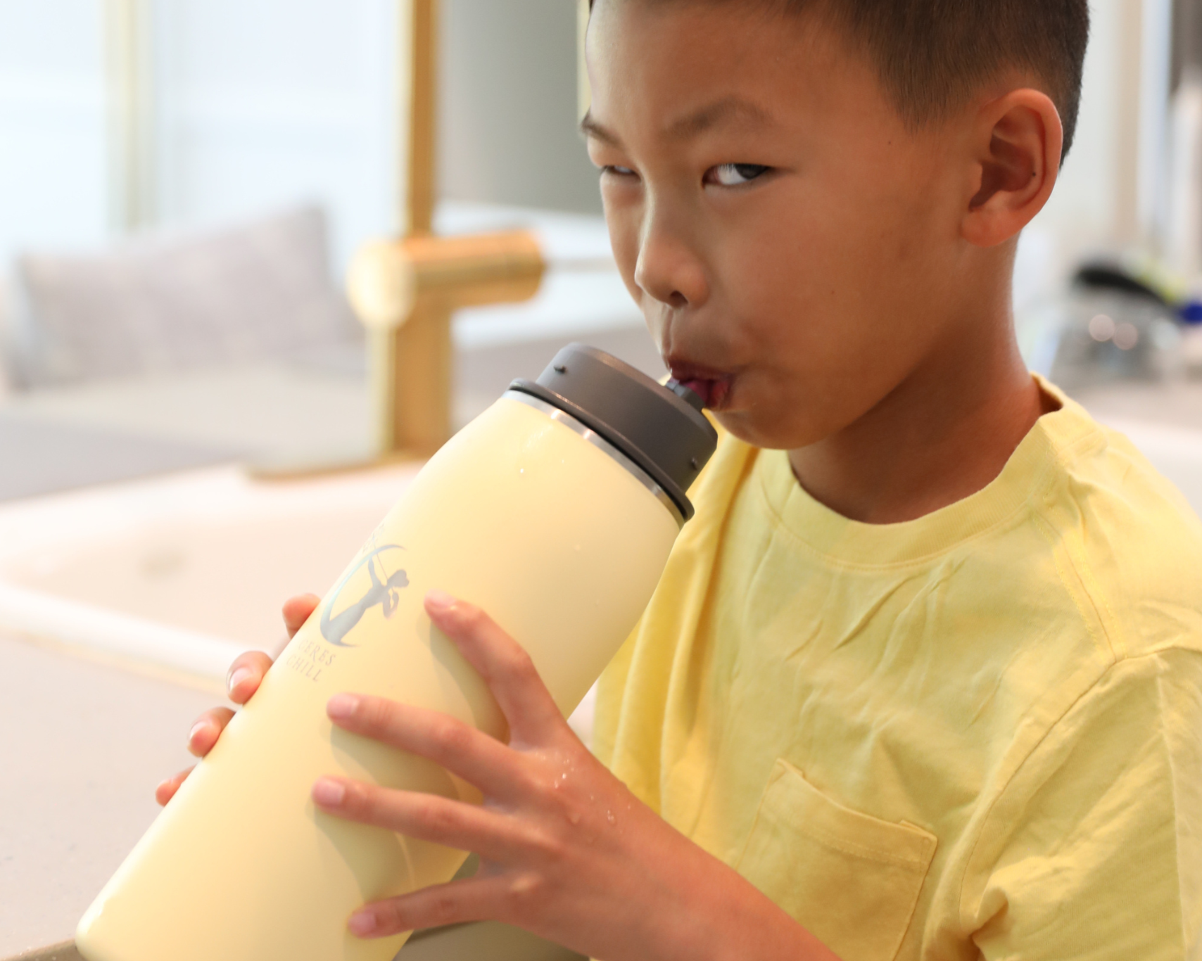 Child holding a yellow chiller in a kitchen setting.