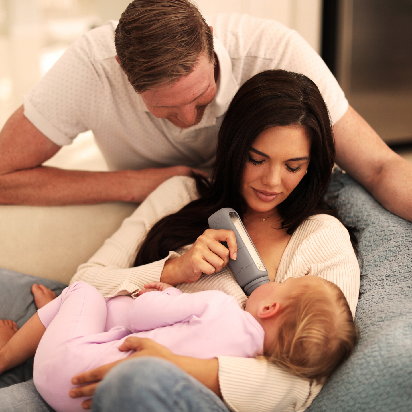 A mother and father using their Bloom Bottle to feed their baby breast milk. 