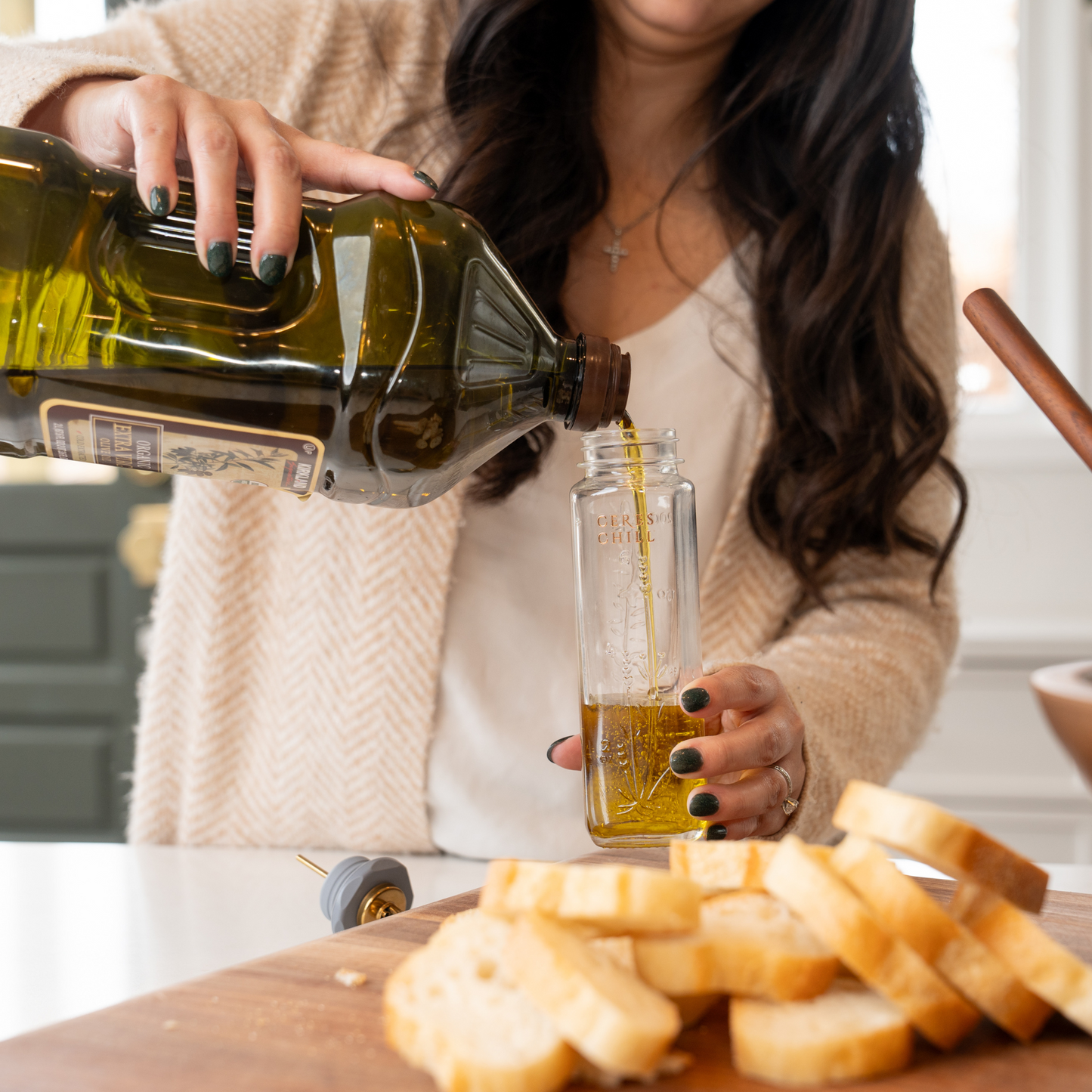 A woman using her bloom bottle as an oil dispenser in the kitchen in her post-breast feeding era. 