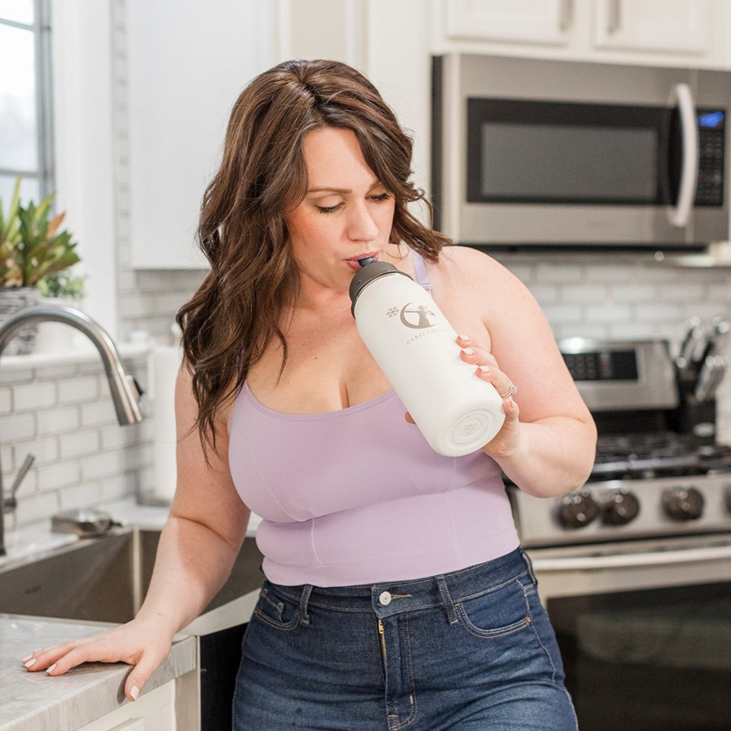 A woman drinking from her Ceres Chill OG Chiller in the kitchen. 