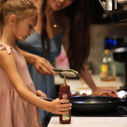 A child, cooking with her mother, using the Bloom Bottle paired with the oil dispenser attachment. 