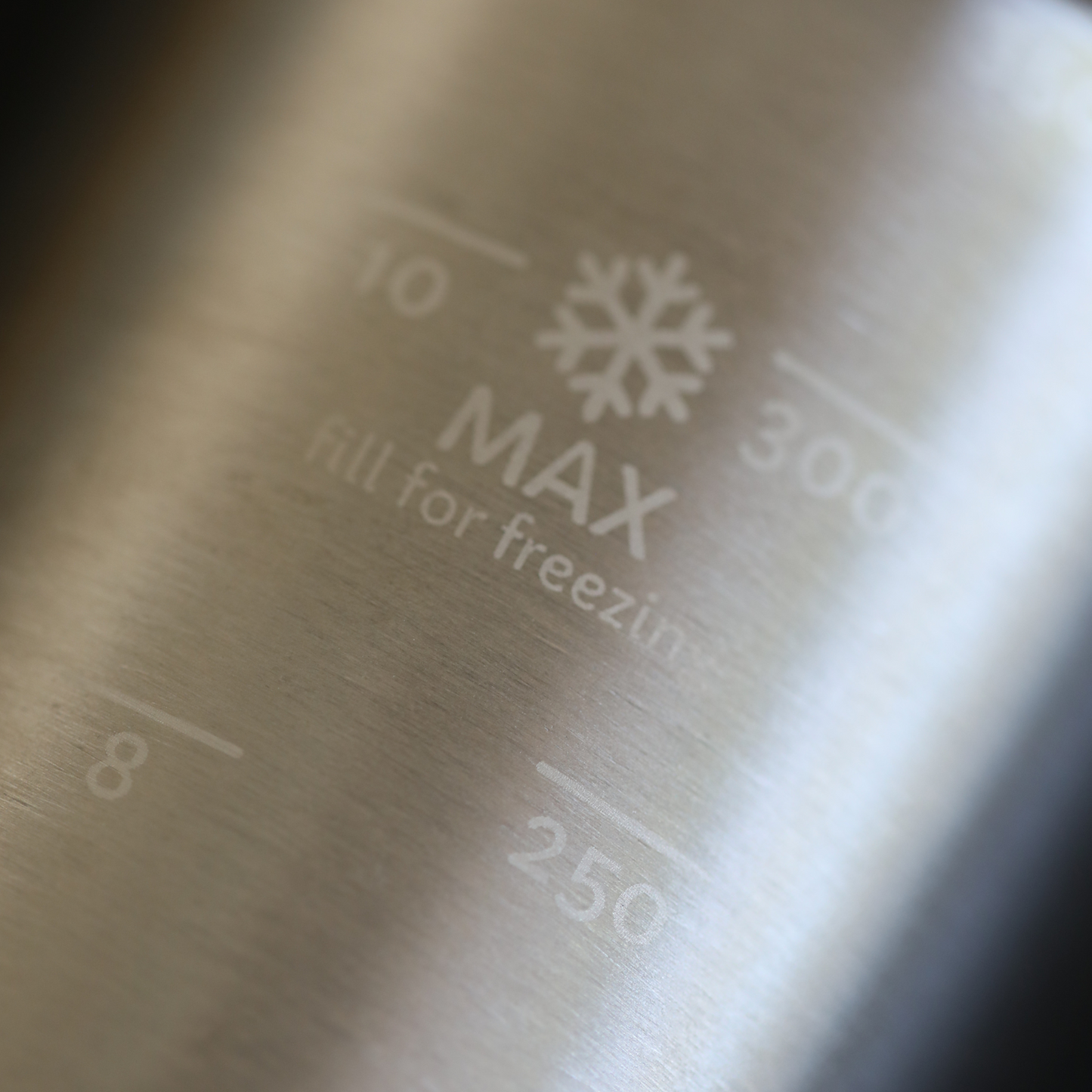 Metal inner chamber container with water fill freezing level markings on a metallic surface.